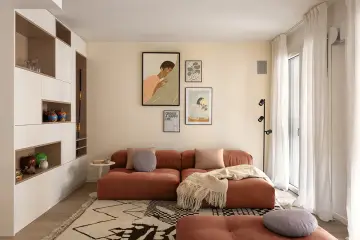 Un soggiorno moderno con divano color terracotta e tappeto geometrico. L'arredamento è pensato per abbinare tappeto e divano, creando un ambiente accogliente.