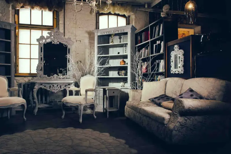 Salotto con divano, poltrone, specchio barocco e librerie. Un esempio di arredamento massimalista che unisce elementi classici e decorazioni elaborate.