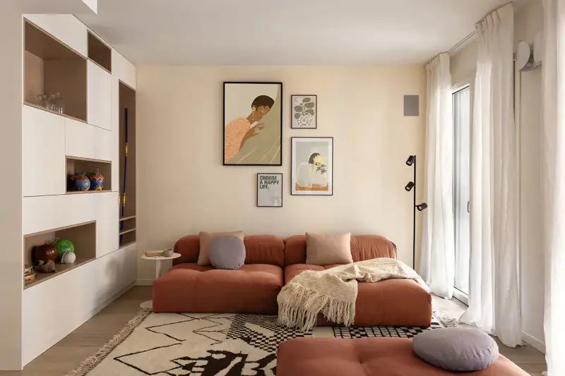 Un soggiorno moderno con divano color terracotta e tappeto geometrico. L'arredamento è pensato per abbinare tappeto e divano, creando un ambiente accogliente.